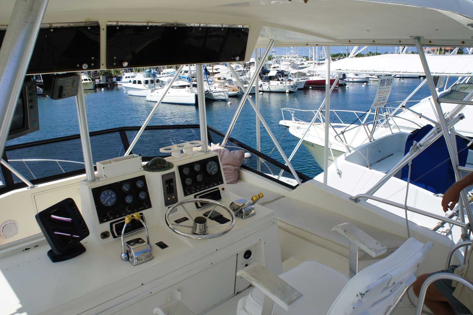 A man is sitting at the helm of a boat in the water
