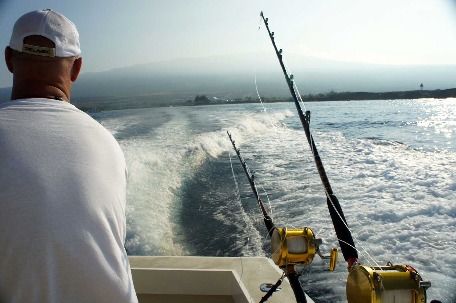 A man on a boat with fishing rods in the water