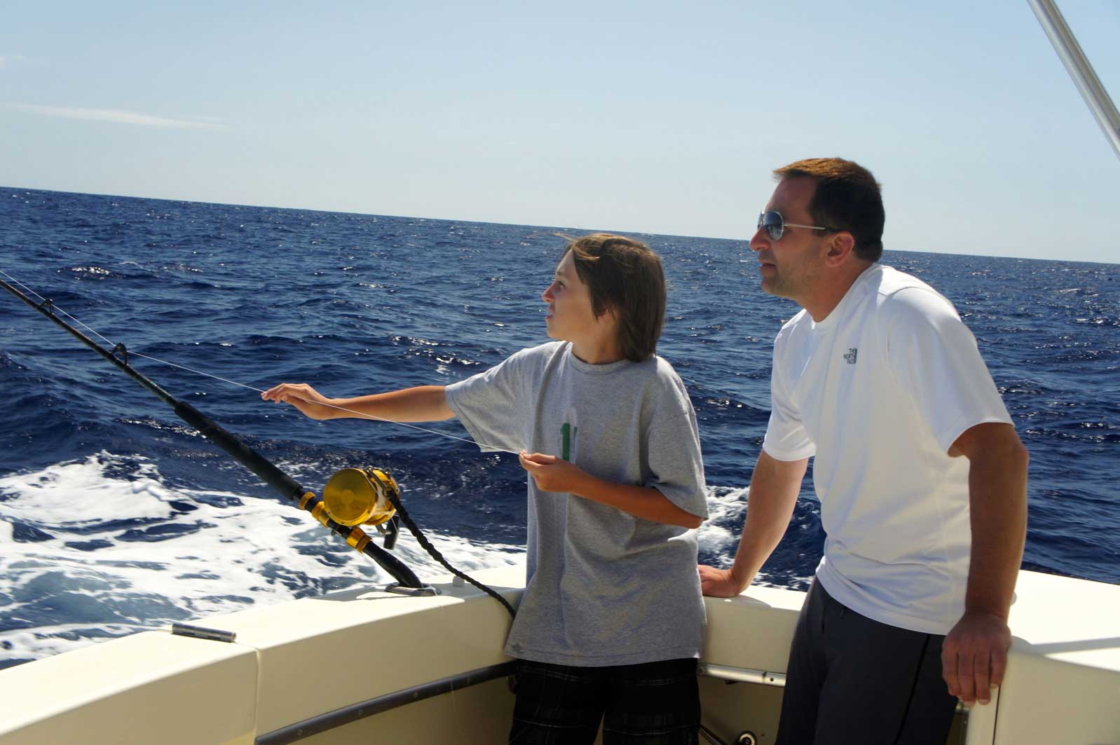 A man and a boy are fishing in the ocean