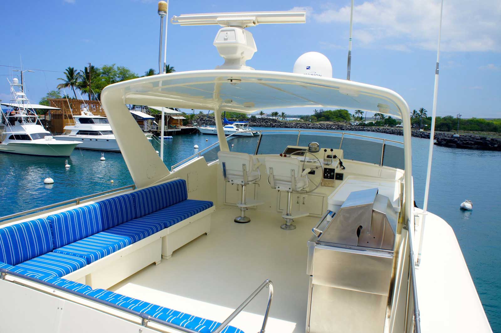 A white boat with blue cushions is in the water