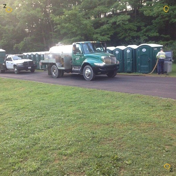 A green truck is parked next to a row of portable toilets