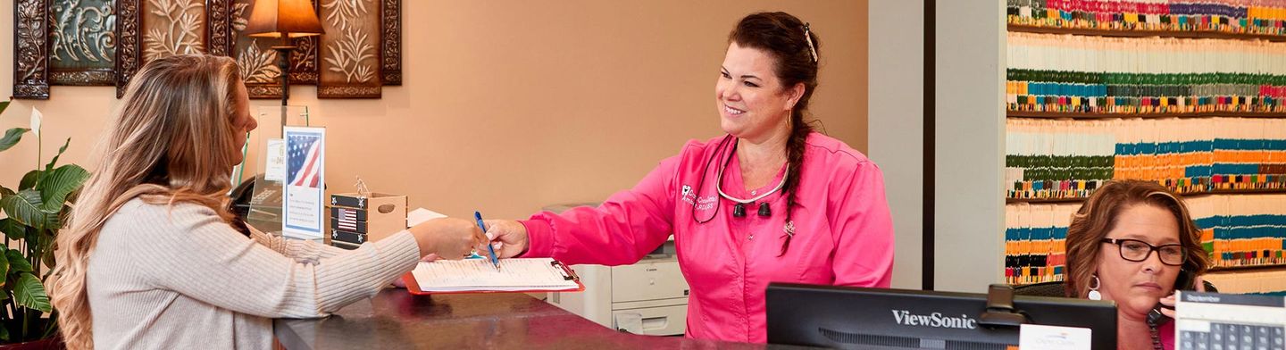 A woman is giving a patient a form at a dental office.
