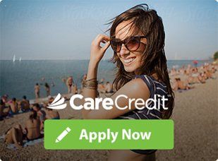 A woman wearing sunglasses is standing on a beach.