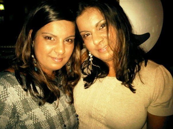 Two women are posing for a picture together in a dark room