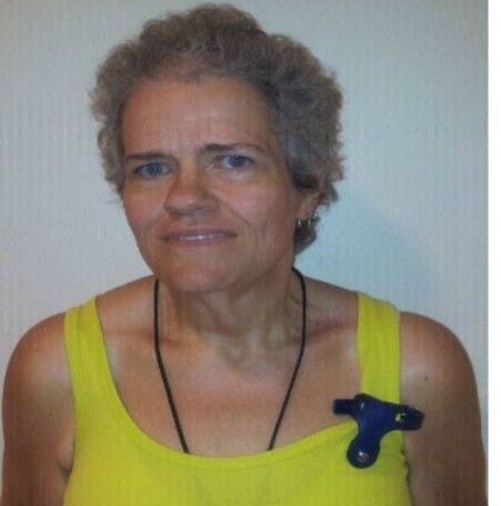 A woman wearing a yellow tank top has a blue brooch on her chest