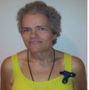 A woman wearing a yellow tank top has a blue brooch on her chest