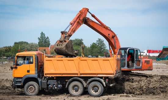Industrial truck loader excavator moving earth and unloading into a dumper truck