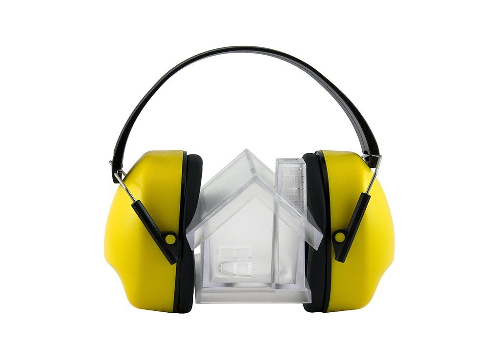A pair of yellow ear protectors with a clear house in the background