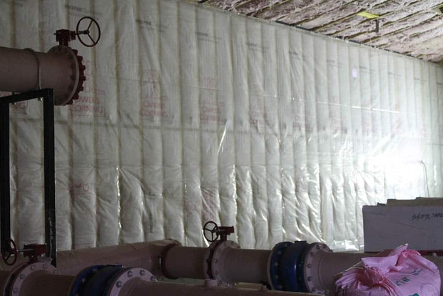 A room filled with pipes and valves covered in insulation.