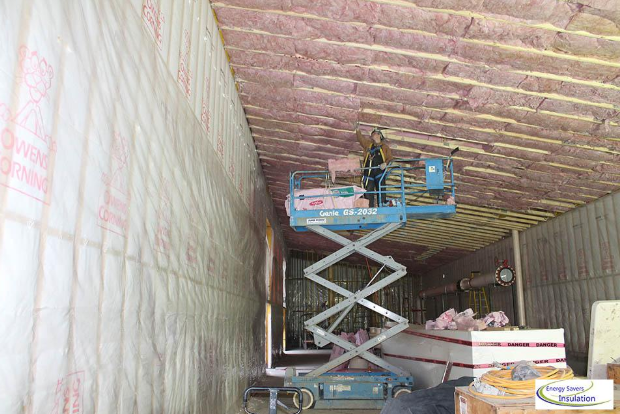 A man is standing on a scissor lift in a building.