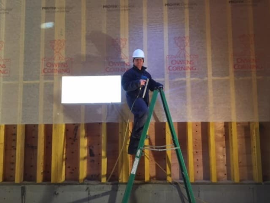 A man standing on a ladder with a hard hat on