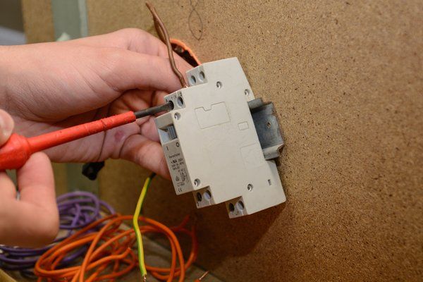 handyman commercial contractor fixing electrical light switch gear and wiring in an office space.