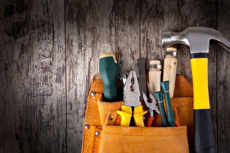 wooden background, tool kit with metal hammer, pliers, screwdrivers and more.