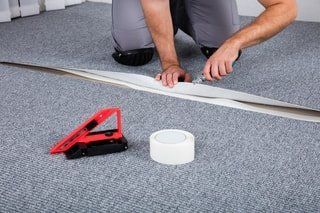 handyman carpet installment. cutting up carpet to fit the design of house's floor. cut with sharp edged knife and measured with handyman ruler.
