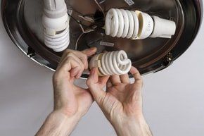 handyman changing one of three LED light bulbs from hallway center light.