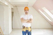 handyman contractor standing in the middle of a room for a painting project. white paint sheet to prevent any mess. taped edges to prevent non painting areas.