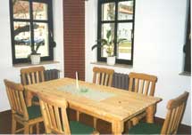 Ein Holztisch und Stühle in einem Raum mit zwei Fenstern.