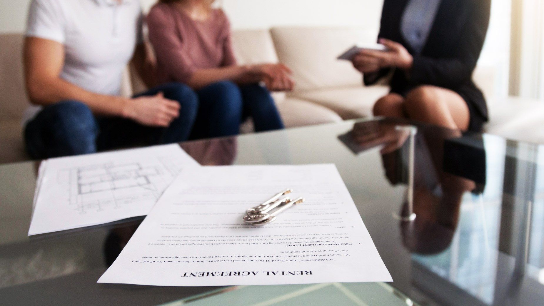 Couple signing rental agreement with a realtor in an apartment.