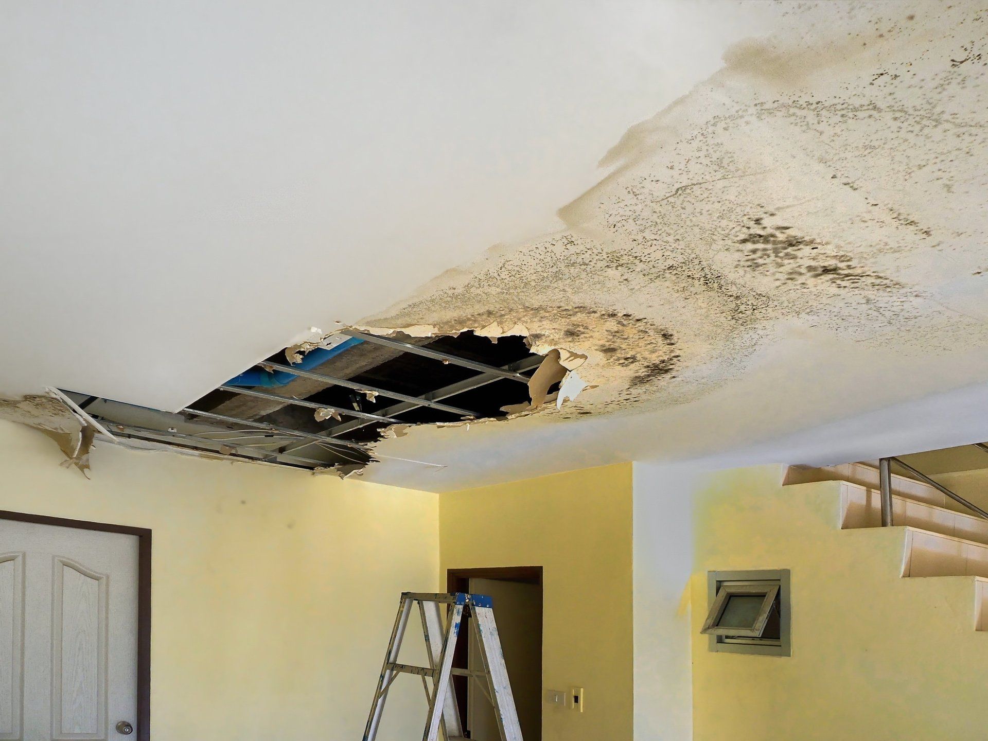 A room with a ladder and a hole in the ceiling