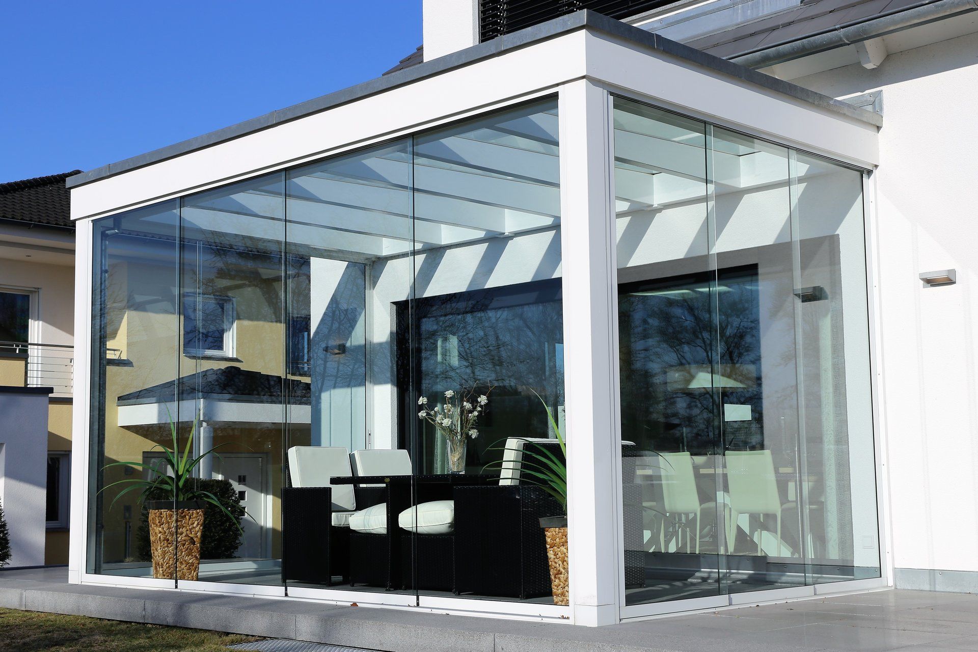 A white house with a glass covered porch with furniture