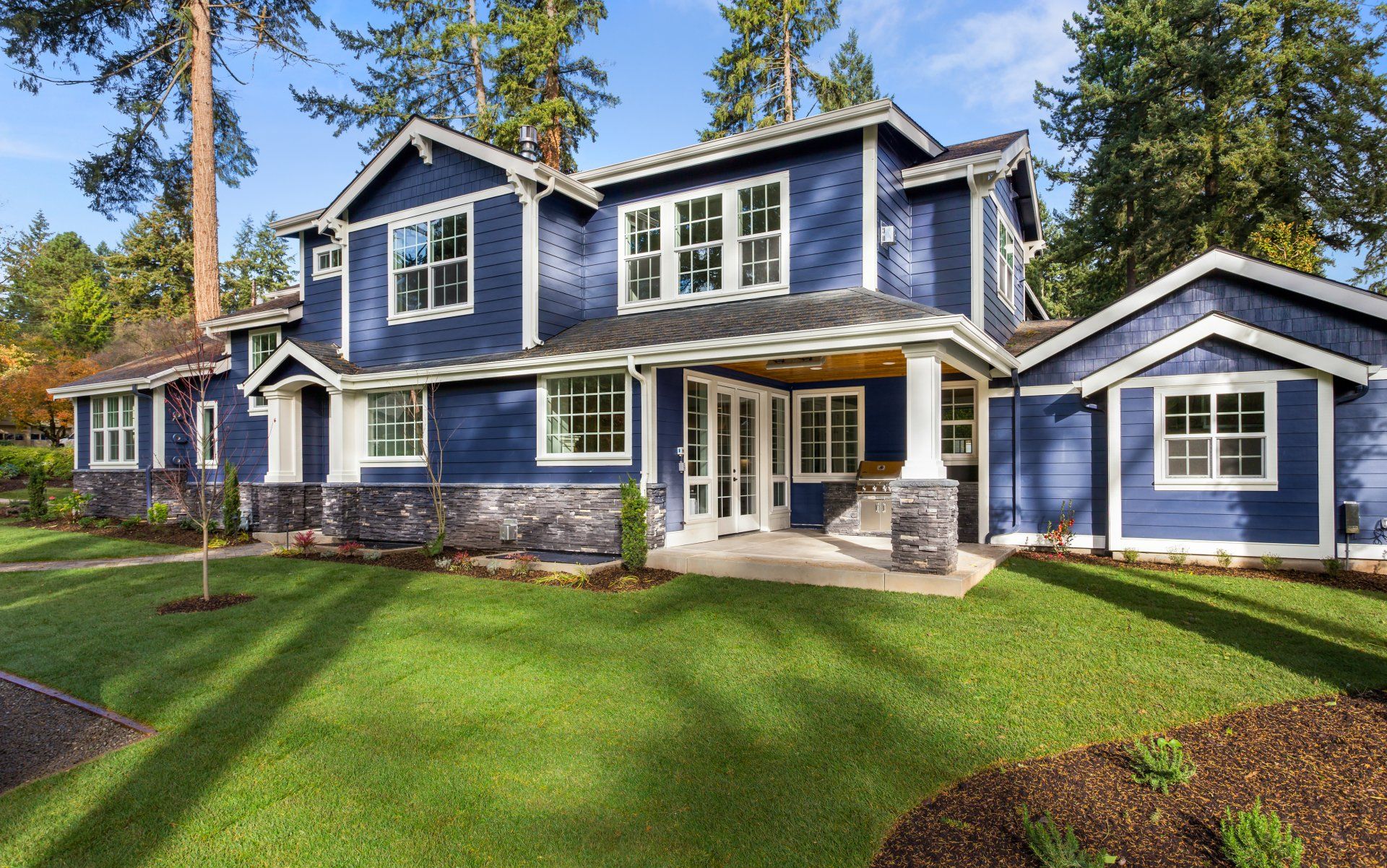 A large blue house with a lush green lawn in front of it.