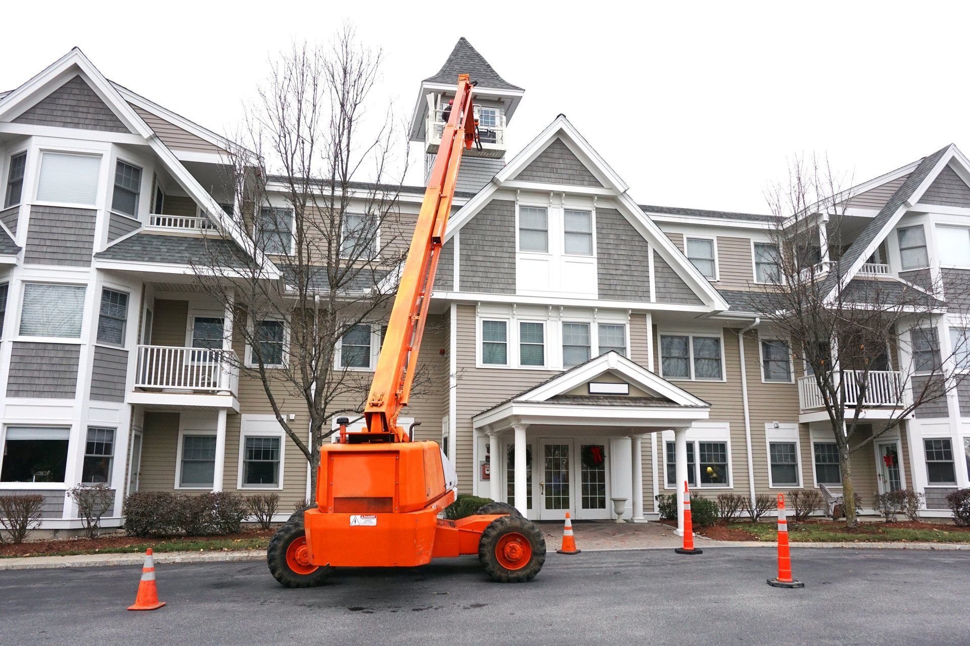 An orange crane is parked in front of a large building