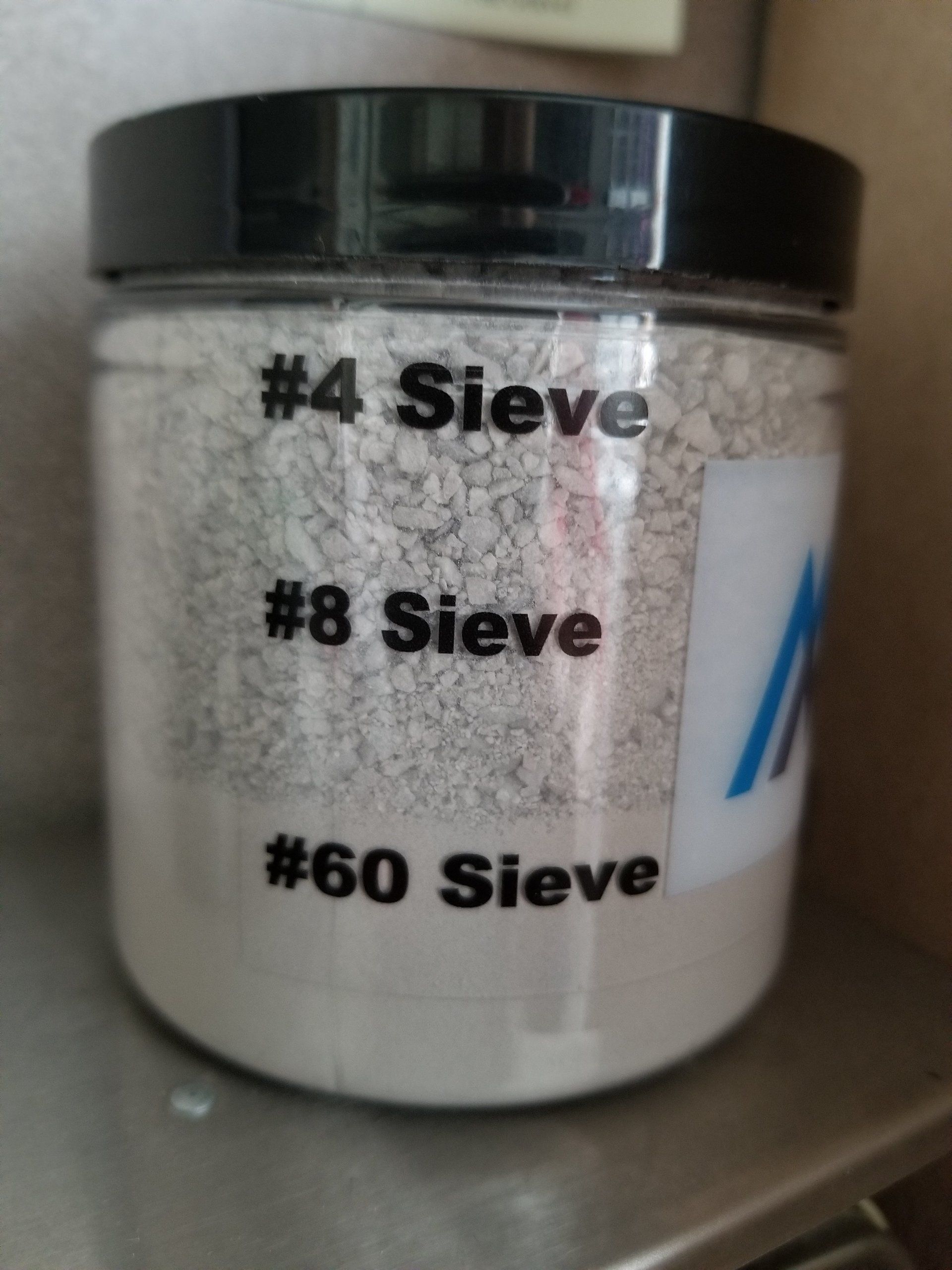 A jar containing three sizes of aggregate, labeled #4, #8, and #60 sieve.