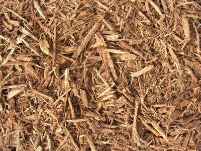 Brown wood chips, mulch, textured surface.