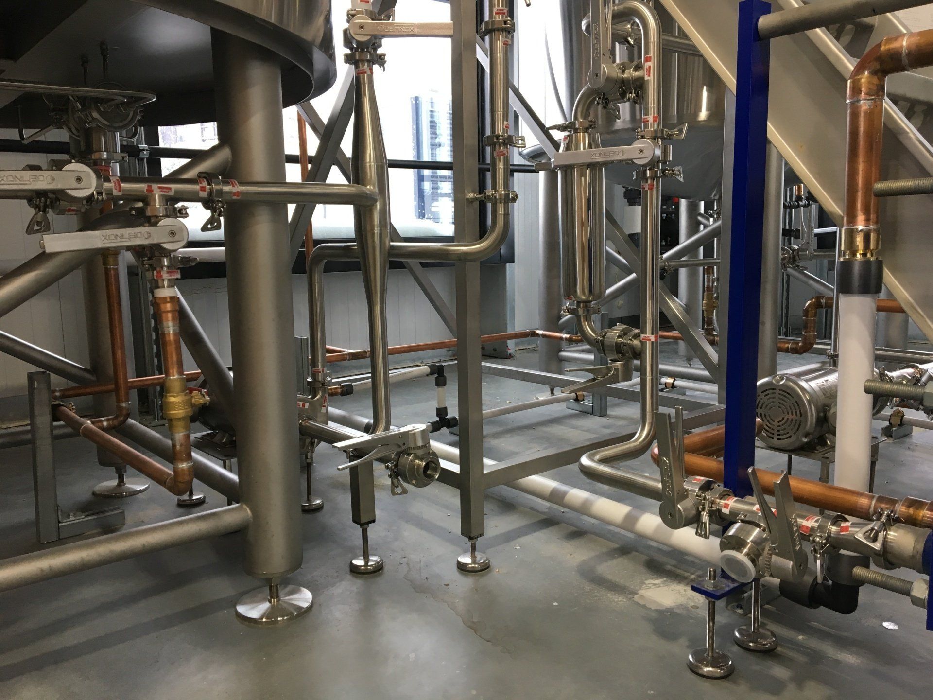 Industrial pipes and equipment with copper and stainless steel components in a factory setting.