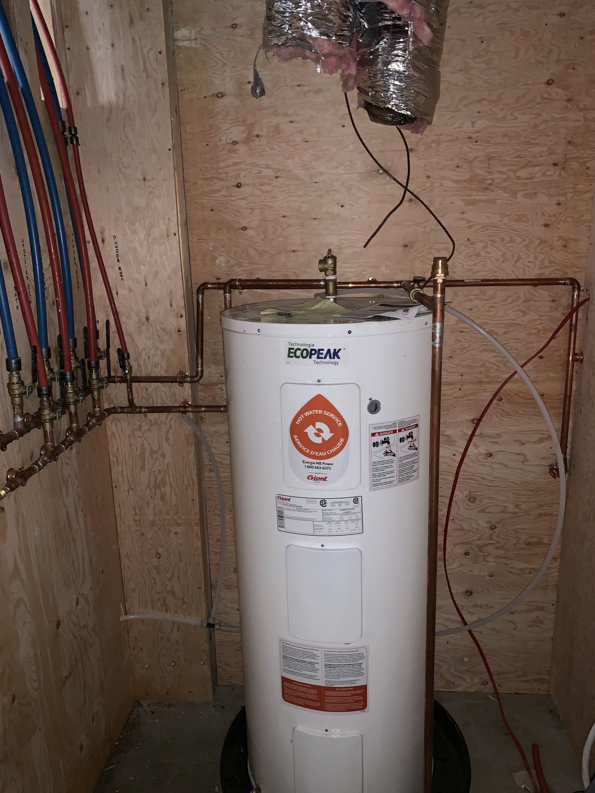 White water heater in a wooden-walled utility closet with connected copper pipes and PEX tubing.