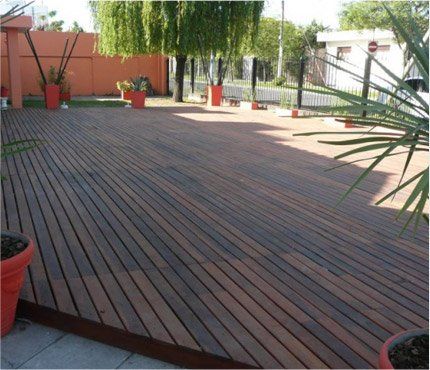 Una terraza de madera con plantas en macetas.