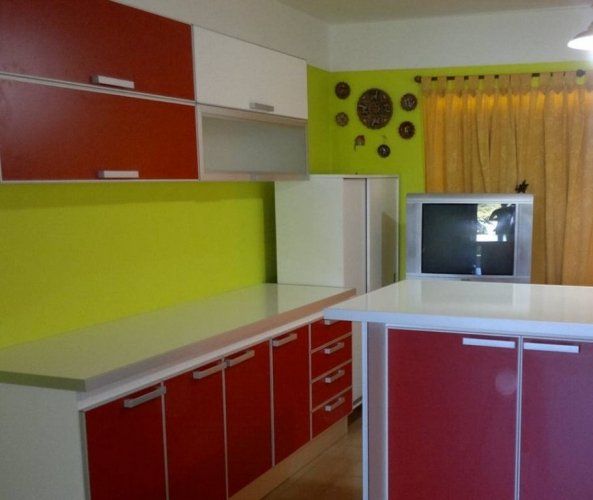 Una cocina con gabinetes rojos y encimeras blancas.