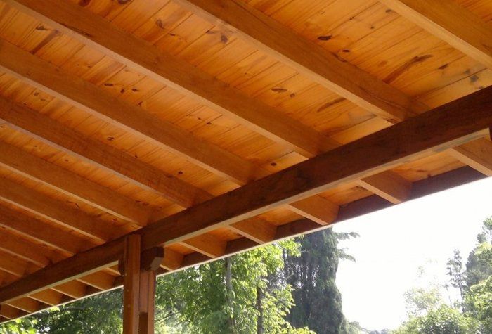 Un primer plano de un techo de madera con árboles al fondo.