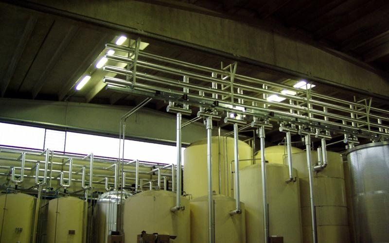 Ambiente industriale con tubazioni e serbatoi in acciaio inox.