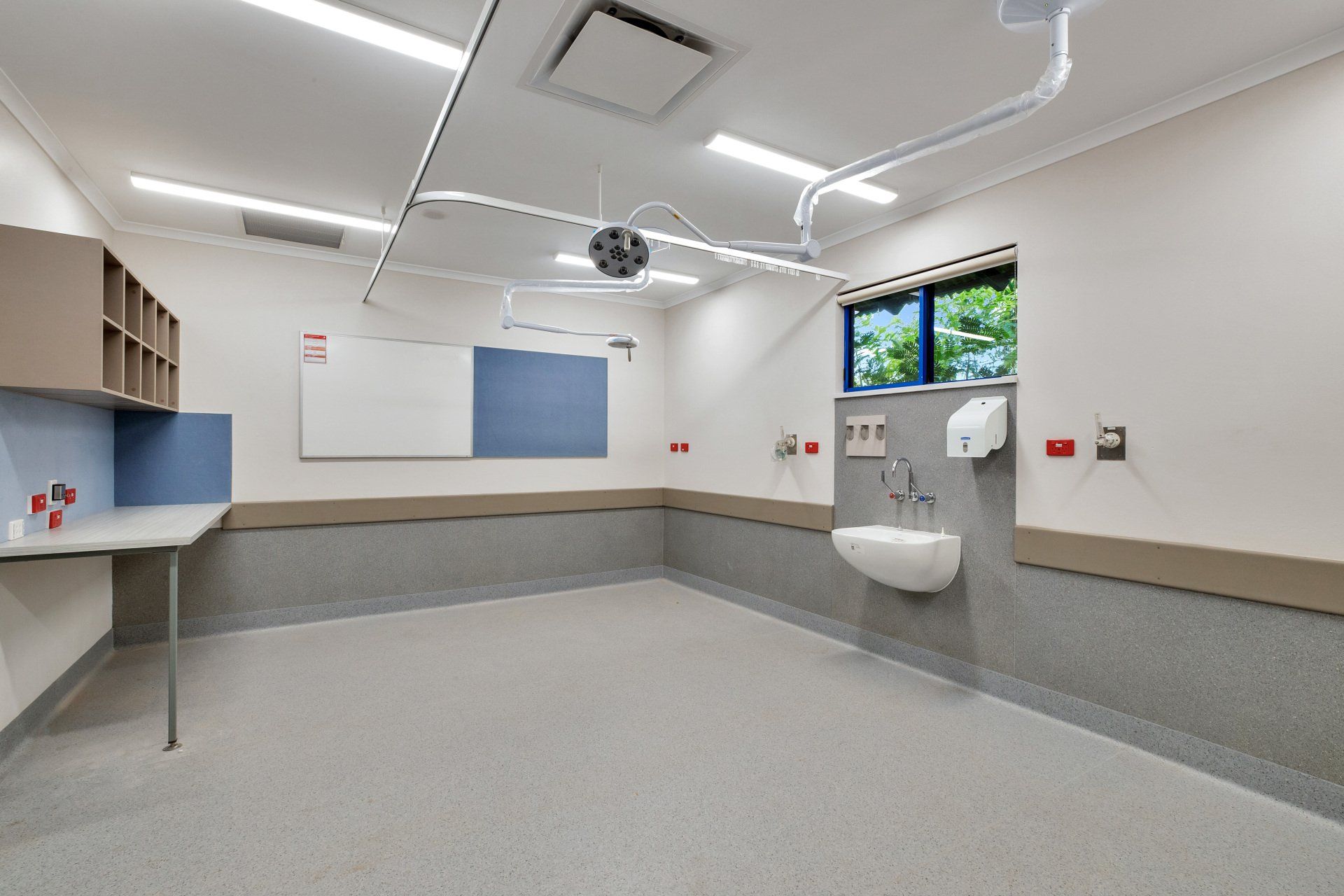 Empty examination room with medical equipment, sink, and counter.