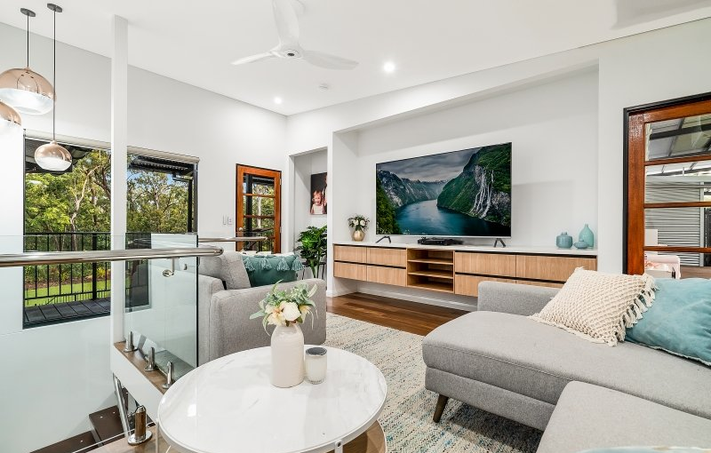 Living room with gray sofa, mounted TV, wooden cabinets, and a round coffee table.