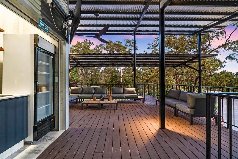 Outdoor patio with a seating area and a cooler. Trees and a sunset are in the background.