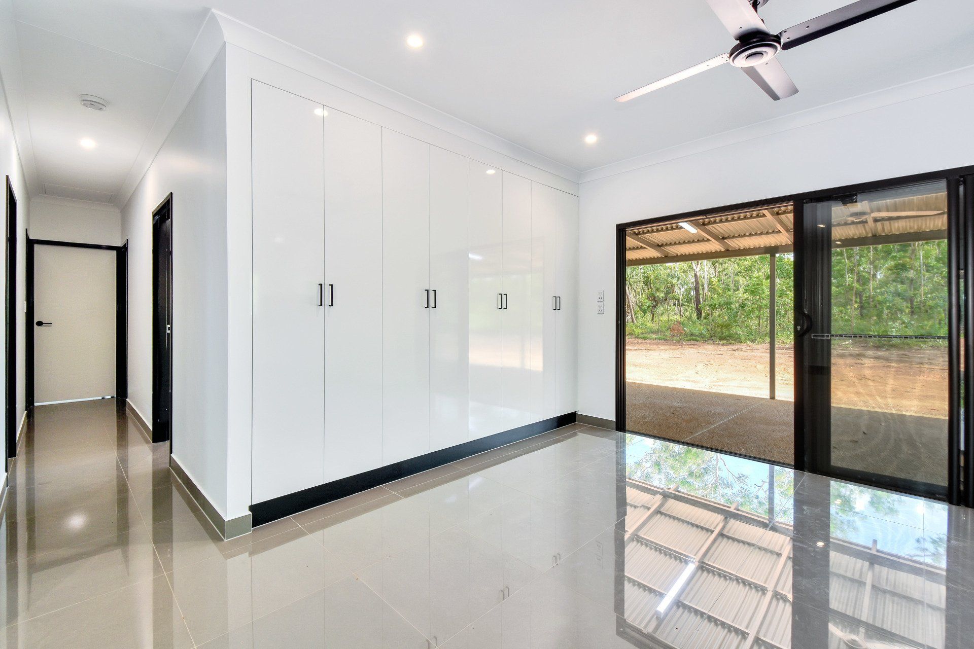 Bright white room with large closet, sliding glass door to porch, and hallway with doors.