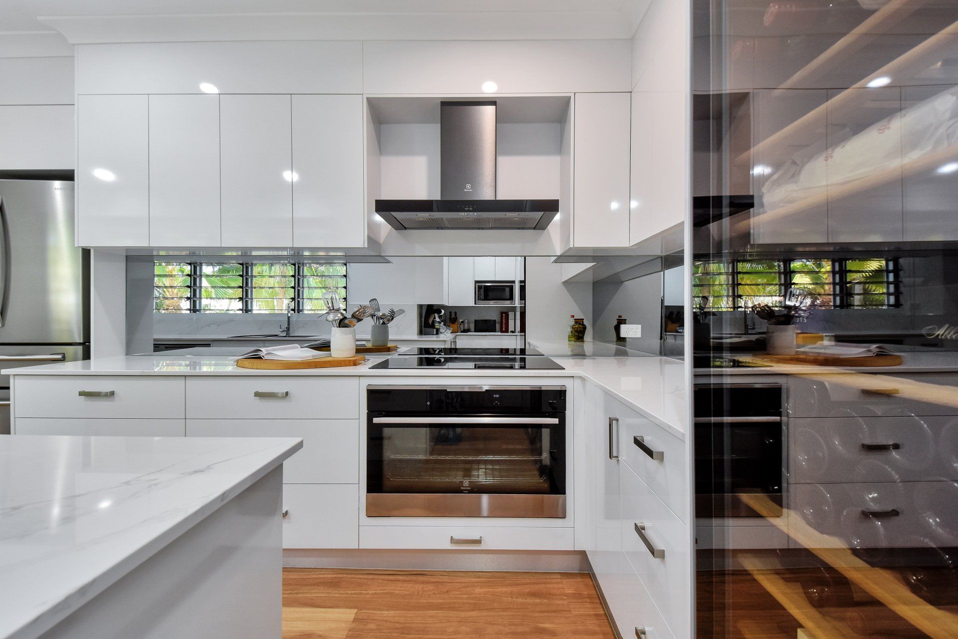 Modern white kitchen with stainless steel appliances and a wine fridge.