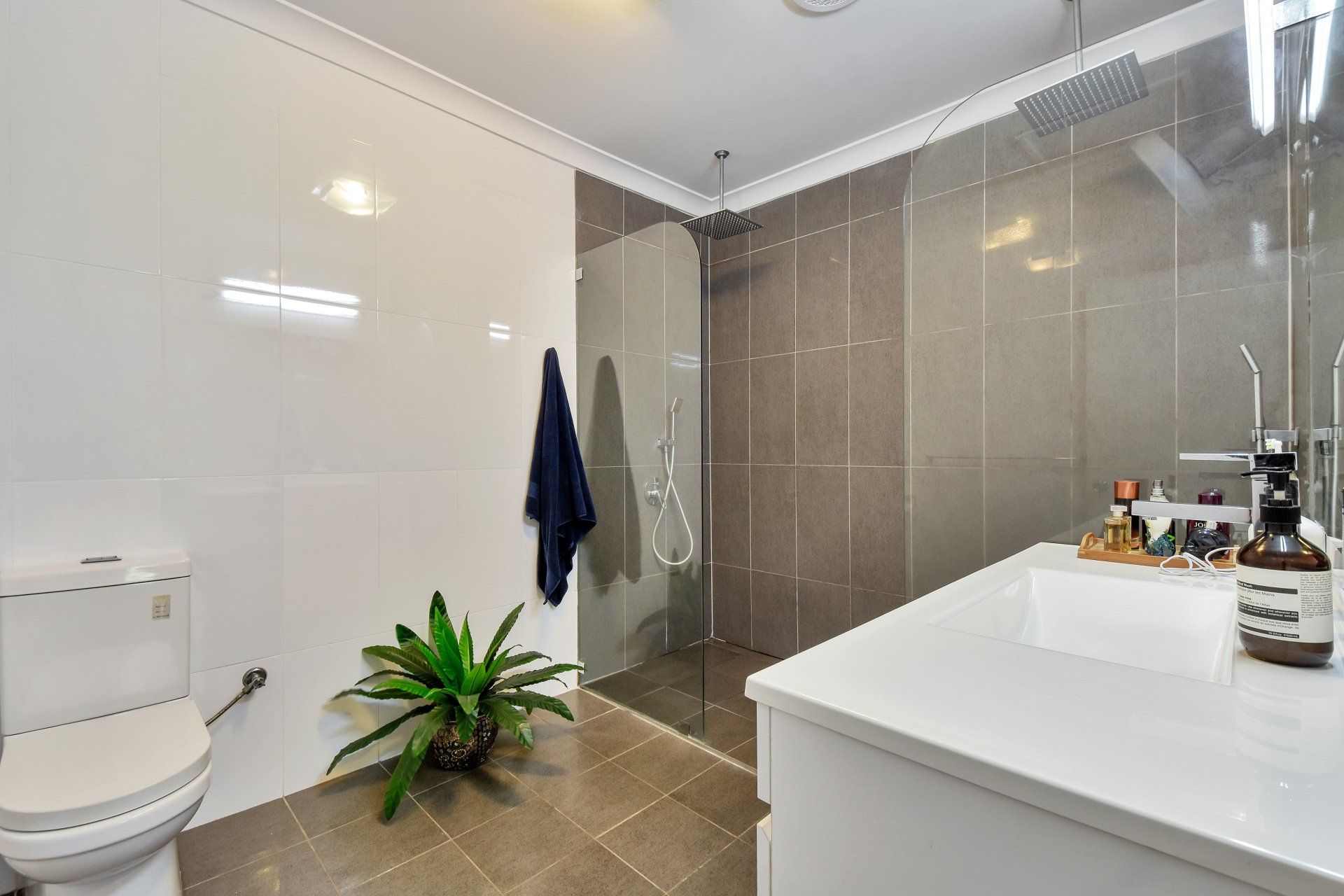 Modern bathroom with white vanity, glass shower, and gray and white tiled walls.