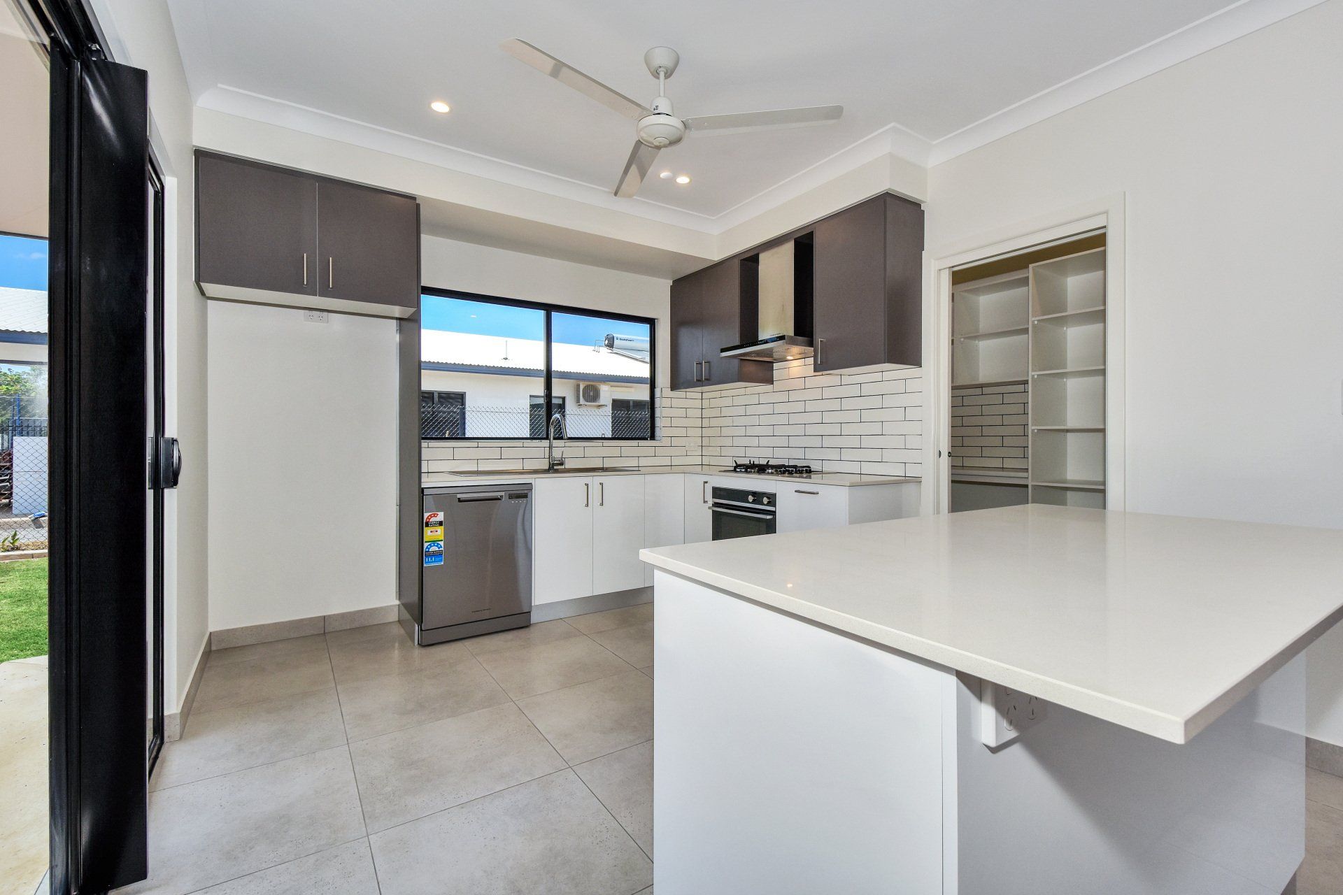 Modern kitchen with white and gray cabinets, island, stainless steel appliances, and sliding door to the yard.