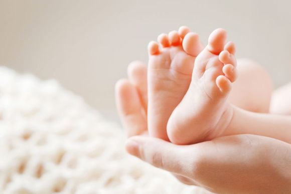 mamma che tiene tra le mani i piedini del suo bambino