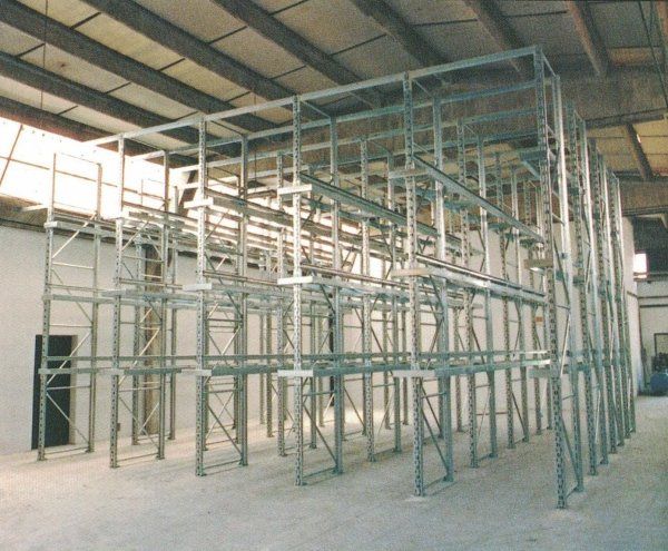 Sistema di scaffalature industriali vuote per pallet installato in un ampio magazzino con soffitto alto.