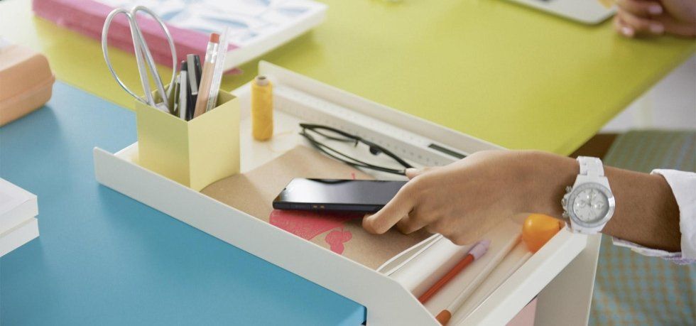 mano che appoggia il cellulare sulla scrivania