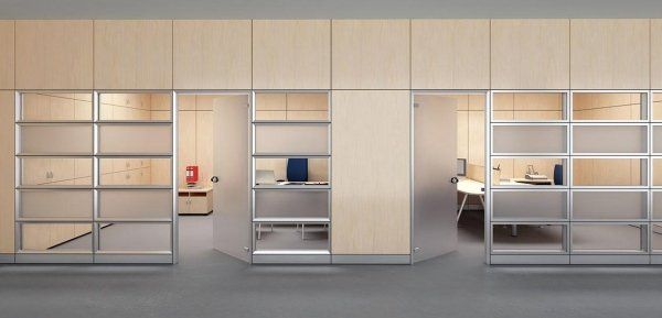 Un corridoio d'ufficio moderno con pareti rivestite in legno chiaro e porte divisorie con pannelli in vetro che conducono a piccoli spazi di lavoro.