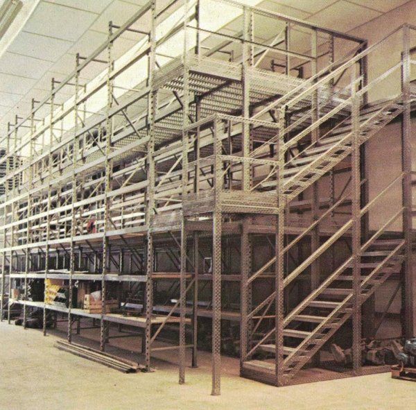 Una scaffalatura metallica a più livelli con scala e passerella integrate, installata in un magazzino.