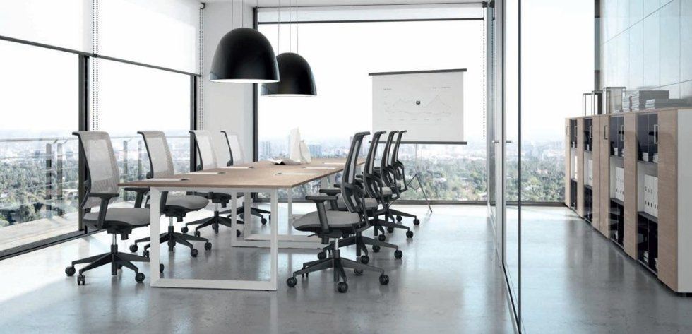 Una sala conferenze moderna e luminosa, con un lungo tavolo in legno, sedie girevoli nere e ampie finestre che si affacciano sulla città.
