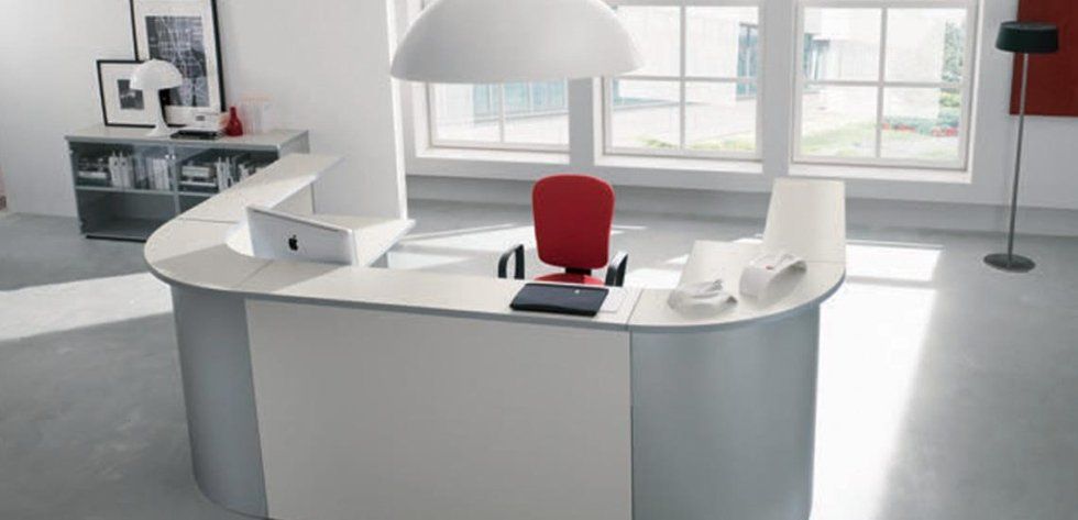 Una reception minimalista bianca con una sedia da ufficio rossa, in un ufficio luminoso e moderno con pavimento grigio chiaro.