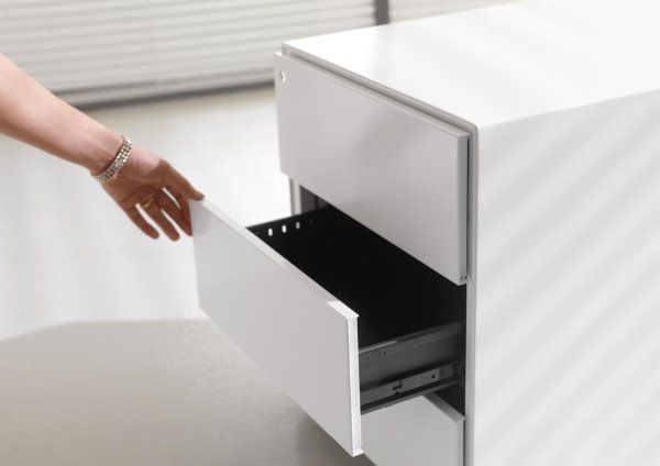 Una mano si protende verso il cassetto aperto di un moderno schedario bianco.