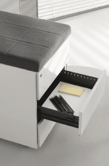 Mobile contenitore bianco con seduta imbottita grigia e cassetto a giorno per penne e blocco note.